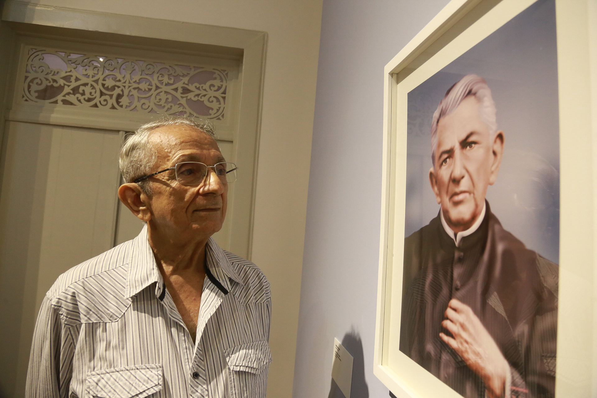 Mestre Julio olha para uma de sua obras que retrata o Padre Cícero